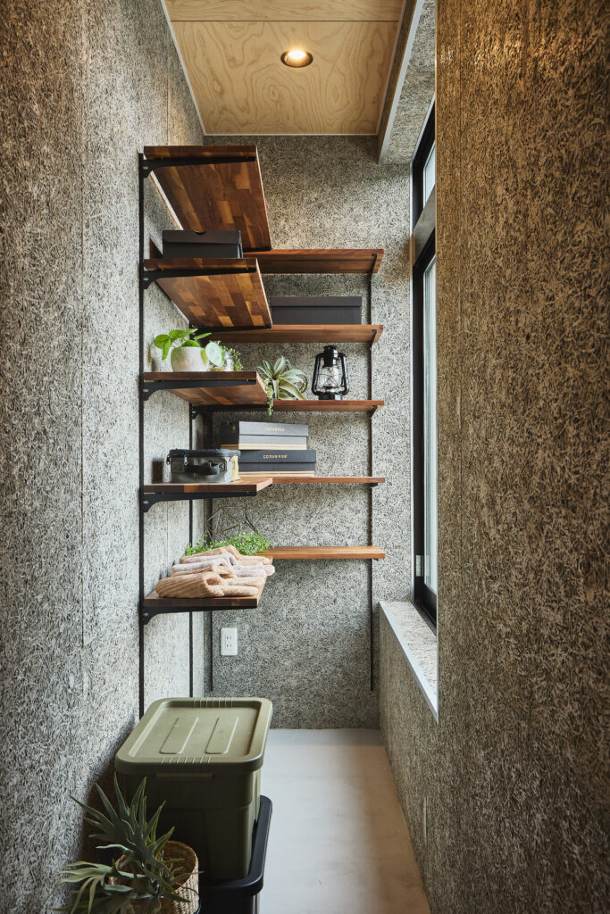 玄関から続く土間のシューズクローク。壁面には木毛セメント板を採用。
キャプション:大容量のシューズクローク。壁には防火性や調湿効果に優れた「木毛セメント板」を貼り、インダストリアルなアクセントに。
