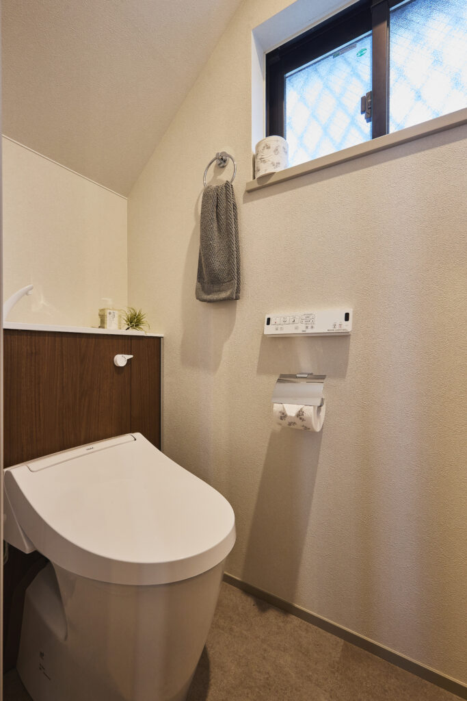 LIXILのJフィットを採用した、スッキリとした見た目のトイレ空間。 キャプション:トイレは「LIXIL Jフィット」。タンクを隠したスタイリッシュなデザインで、収納力も兼ね備えています。