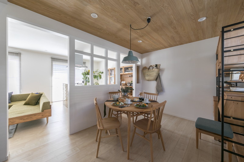 戸建てリノベーションのダイニングルーム。木目調の天井と、リビングからの光を取り込む造作の室内窓。