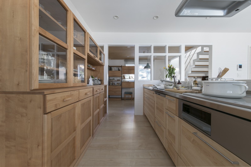 対面キッチン背面の木製大容量カップボード。生活感を隠す戸建てリノベーションの収納計画。