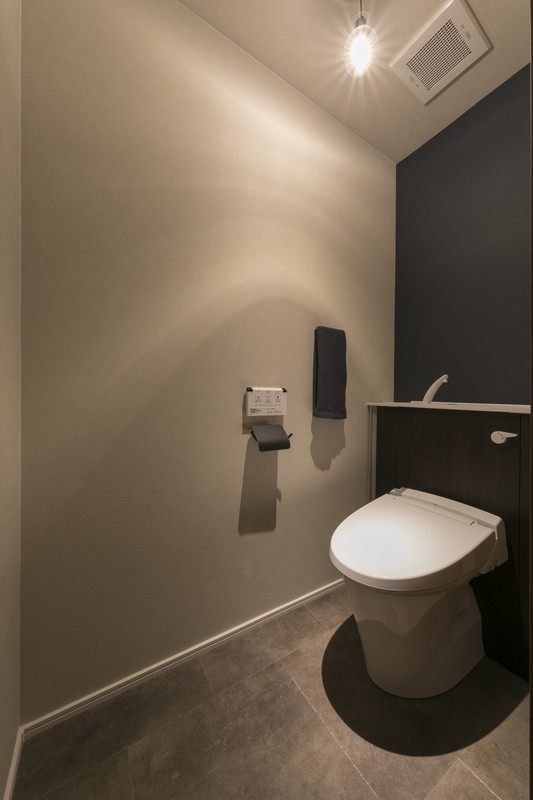 八王子市の中古戸建てリノベーション事例。ダークカラーのアクセントクロスを採用したヴィンテージテイストのトイレ。