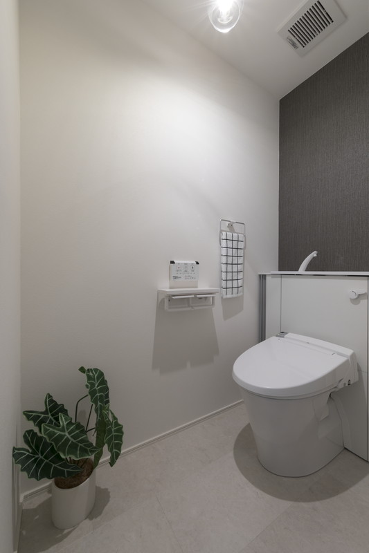 戸建てリノベーションのトイレ空間。グレーのアクセントクロスと清潔感のある設備。