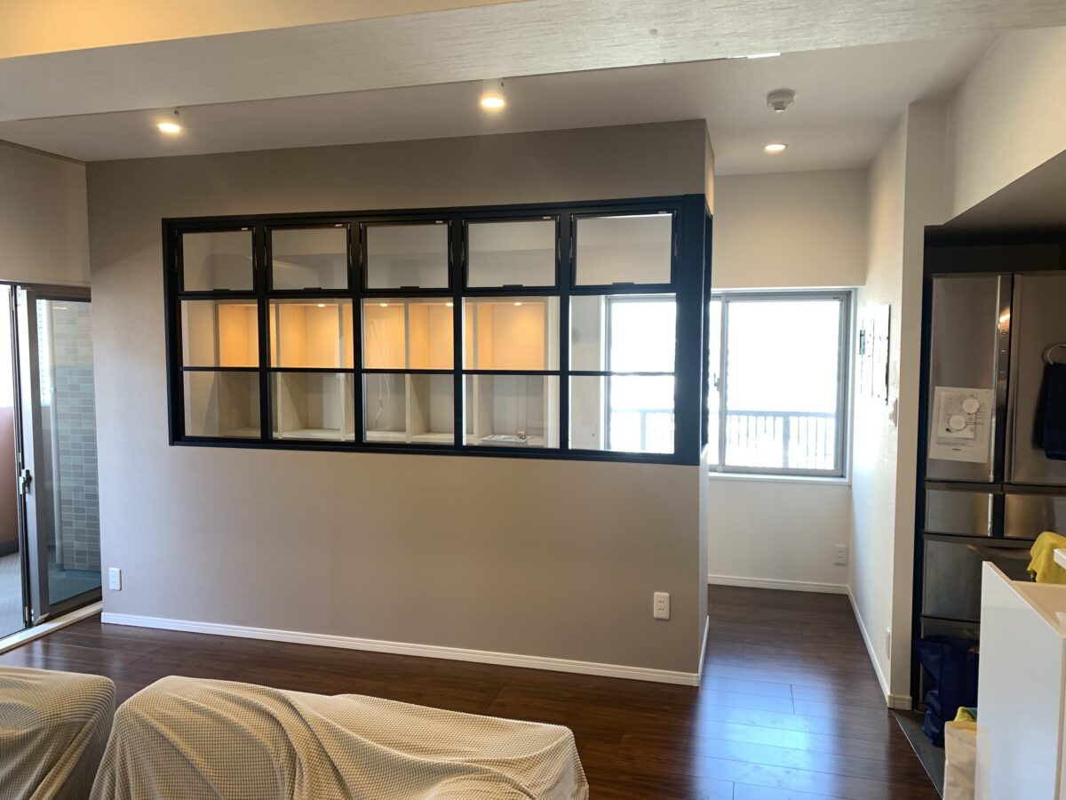 リビングの一角に造作した黒縁ガラスの間仕切りとダウンライト付き収納棚